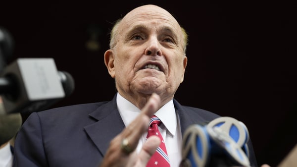 Rudy Giuliani speaks to reporters as he leaves his apartment building in New York on Wednesday to be booked in Atlanta.